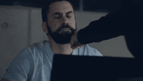a man with a beard is looking at a computer screen