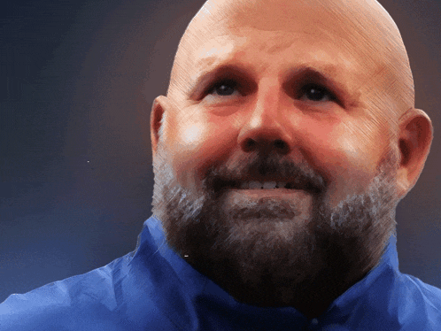 a bald man with a beard and a blue shirt is smiling