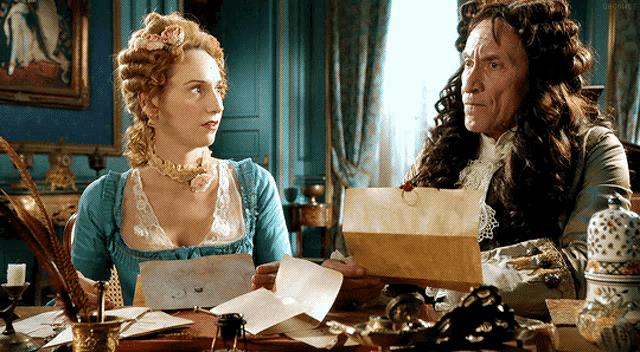 a man and a woman are sitting at a desk looking at a piece of paper