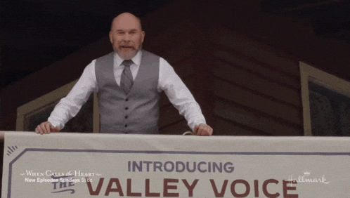 a man stands behind a sign that says introducing valley voice