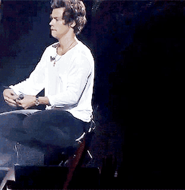 a man in a white shirt and black pants is sitting on a stage