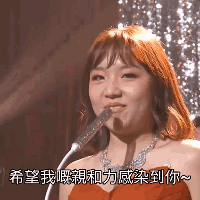 a woman in a red dress is singing into a microphone with chinese writing surrounding her