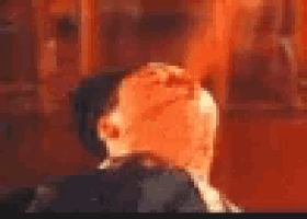 a close up of a man 's head in a dark room with a red background .