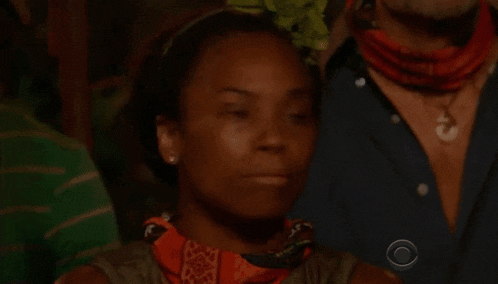 a woman wearing a bandana and earrings is standing in a crowd of people .
