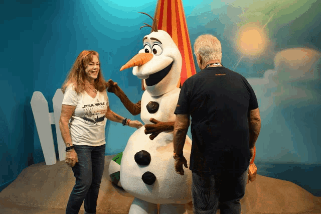 a woman wearing a star wars t-shirt is standing next to a snowman