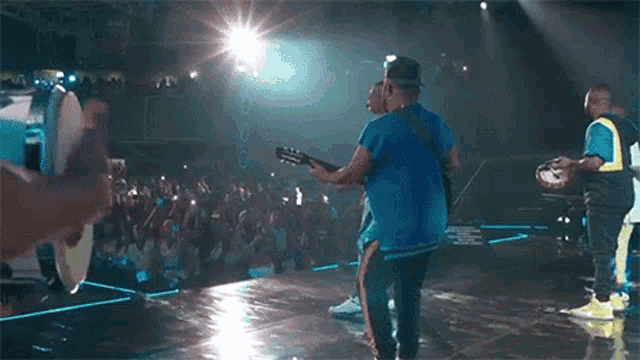 a man is playing a guitar on stage in front of a crowd of people .