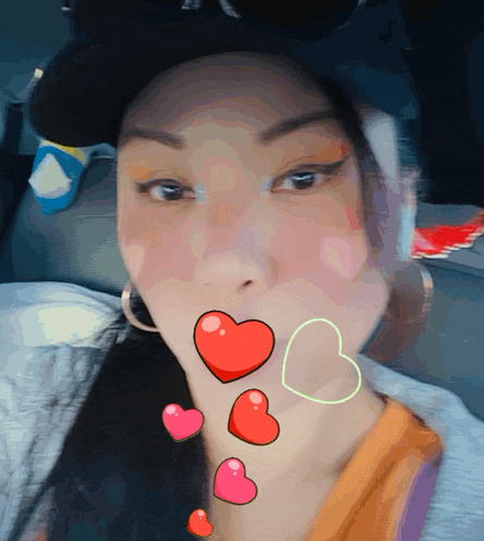 a woman wearing a hat and earrings is surrounded by hearts on her face