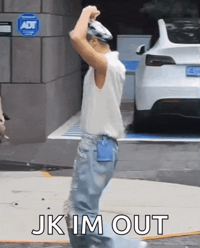 a man is standing in front of a white car with the words jk im out written on it