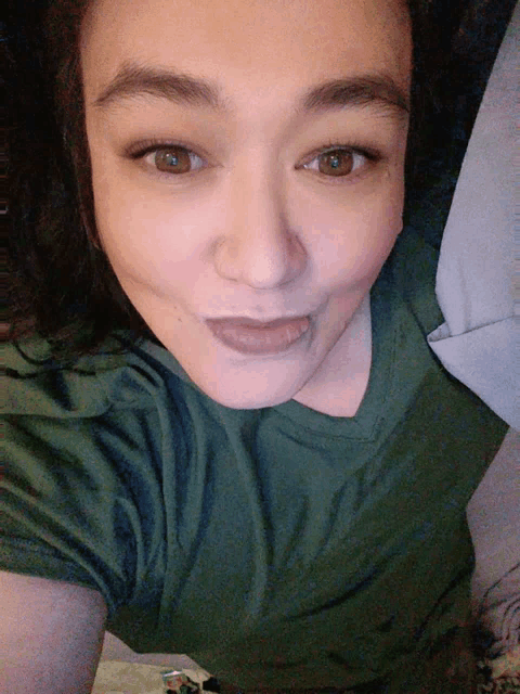 a woman wearing a green shirt is making a funny face