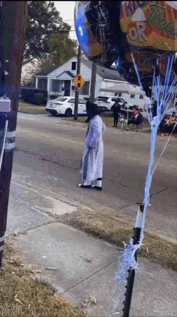 a man in a white coat is walking down the street with a balloon that says trick or treat