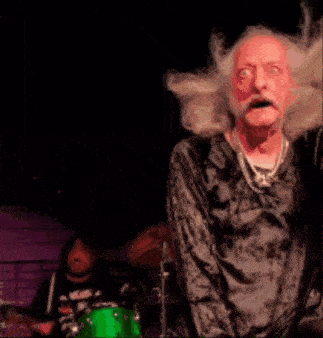 a man with long hair and a beard is playing drums
