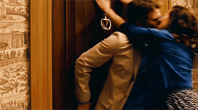 a man and woman are kissing in front of a door with a door knocker on it