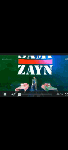 a man is standing in front of a sign that says zayn on it