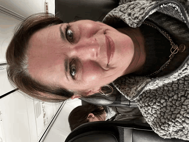 a woman sitting on an airplane with the word exit visible on the ceiling