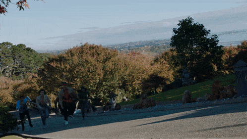 a group of people are running up a hill with trees in the background