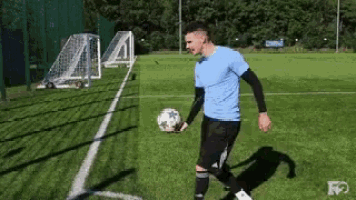 a man in a blue shirt is holding a soccer ball on a field .