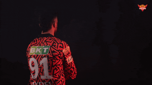 a man in a red and black shirt with the name howzzat