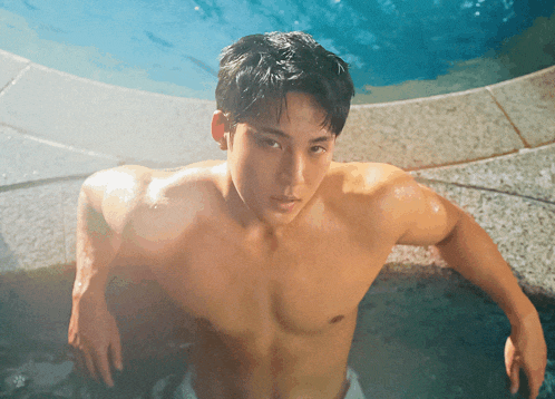 a shirtless man is leaning on the edge of a swimming pool