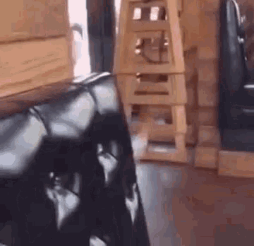 a black leather chair is sitting in a restaurant next to a wooden ladder .