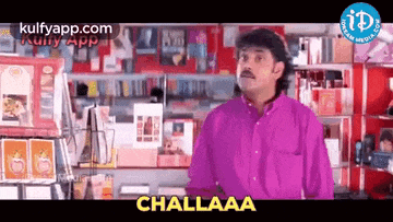 a man in a purple shirt is standing in front of a store and says challaa .