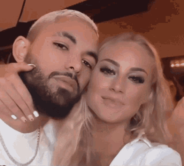 a man with a beard and a woman with long blonde hair are posing for a picture together .