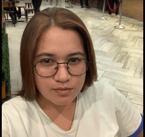 a woman wearing glasses and a white shirt poses for a picture