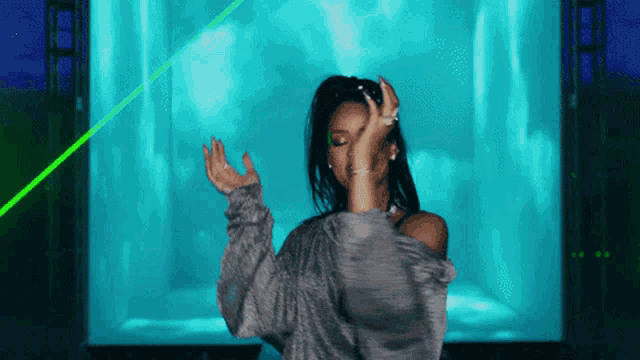a woman is dancing in front of a blue and green light