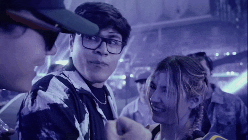 a man with glasses is talking to a woman in a crowd