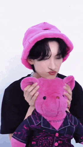 a man wearing a pink hat and holding a pink teddy bear .