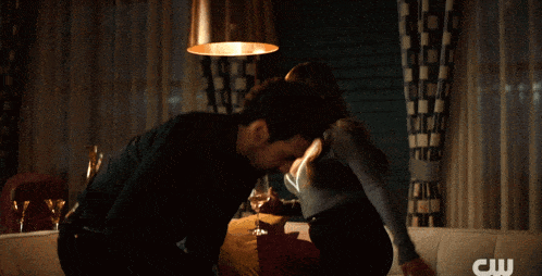 a man and woman are kissing in a room with a cw logo