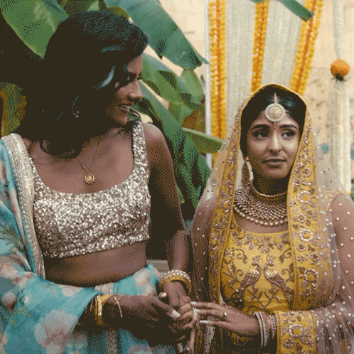 two women are standing next to each other and one is wearing a gold top