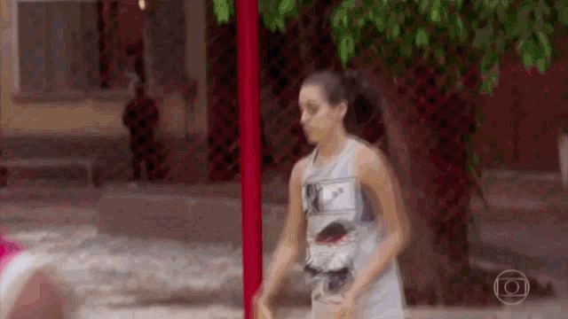 a woman is standing in front of a red fence holding a basketball .