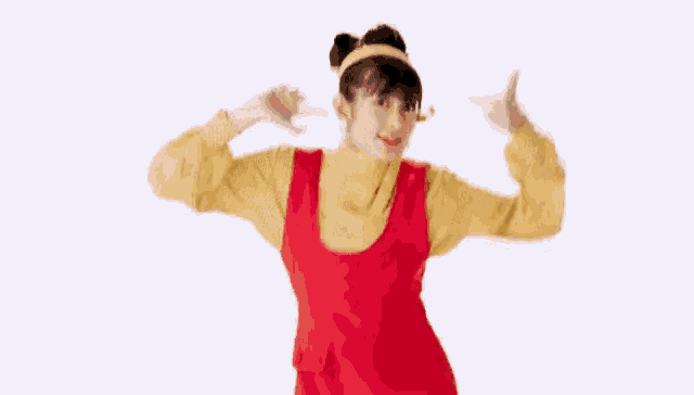 a woman in a red dress and yellow shirt is dancing with her hands in the air .