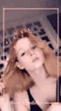 a woman with red hair is taking a selfie with a pink frame around her head .