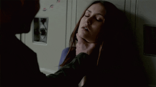 a man is holding a woman 's neck in front of a locker .