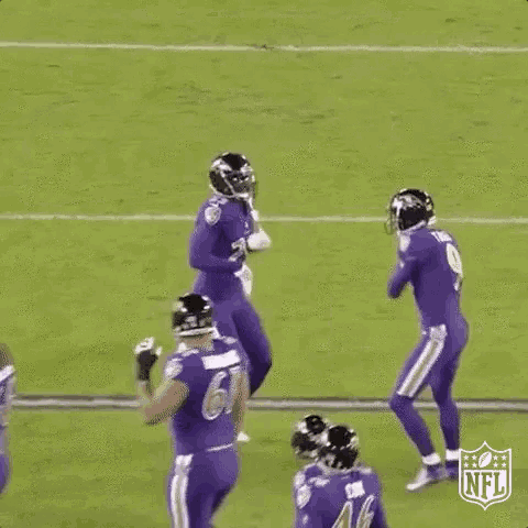 a group of football players are jumping in the air on a field during a game .