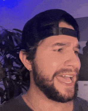 a man with a beard is wearing a black hat and making a funny face