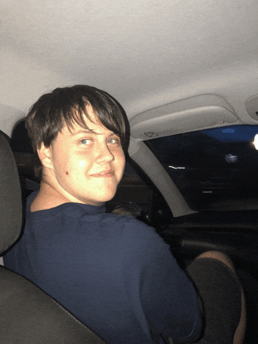a young man sitting in the back seat of a car
