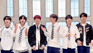 a group of young men wearing school uniforms and ties are standing next to each other in front of a window .