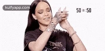 a woman wearing a black shirt and bracelets is holding her hands together in front of her face .