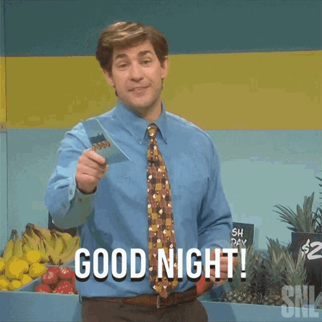 a man in a blue shirt and tie is holding a piece of paper and says good night