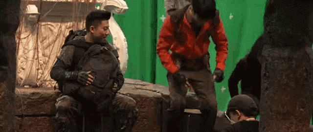 a man with a backpack is sitting on a rock next to another man