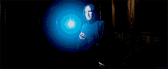 a man in a hooded robe is holding a blue light in his hand