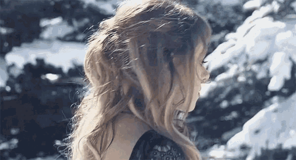 a woman in a black dress is standing in the snow .