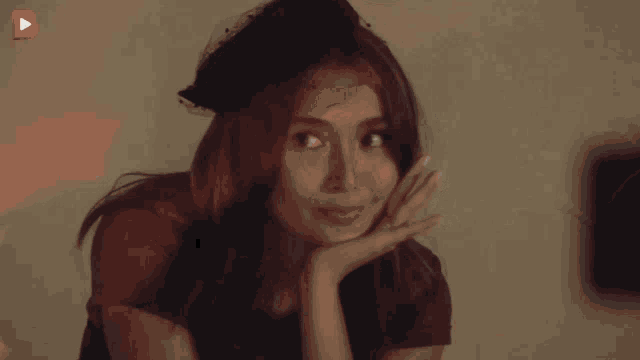 a woman wearing a blue hat with a veil looks at the camera