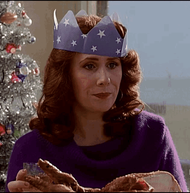 a woman wearing a purple sweater and a paper crown with stars on it