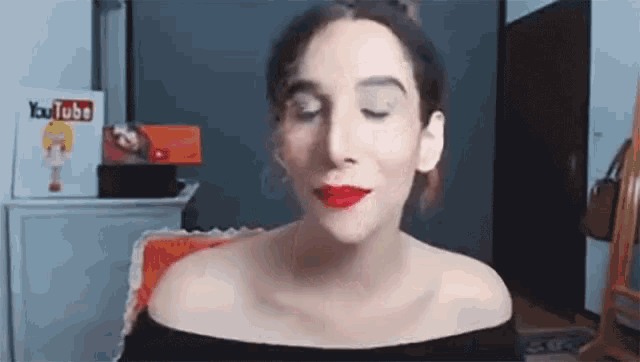 a woman wearing red lipstick is sitting in front of a mirror in a room .
