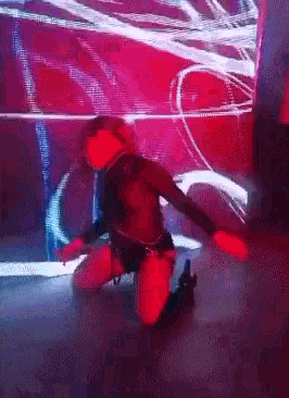 a woman is kneeling down on the floor in front of a red background