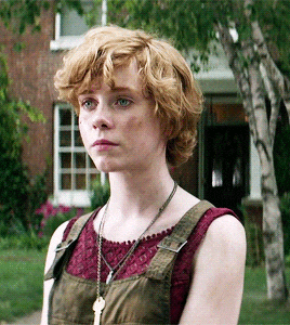a young woman wearing overalls and a necklace with a key