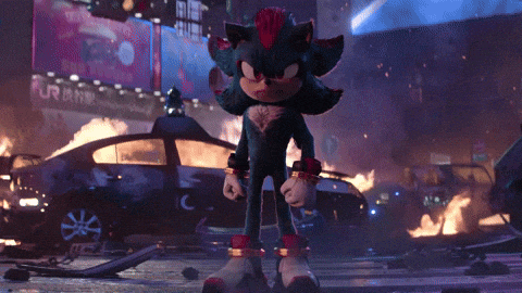 shadow the hedgehog stands in front of a burning car in a city